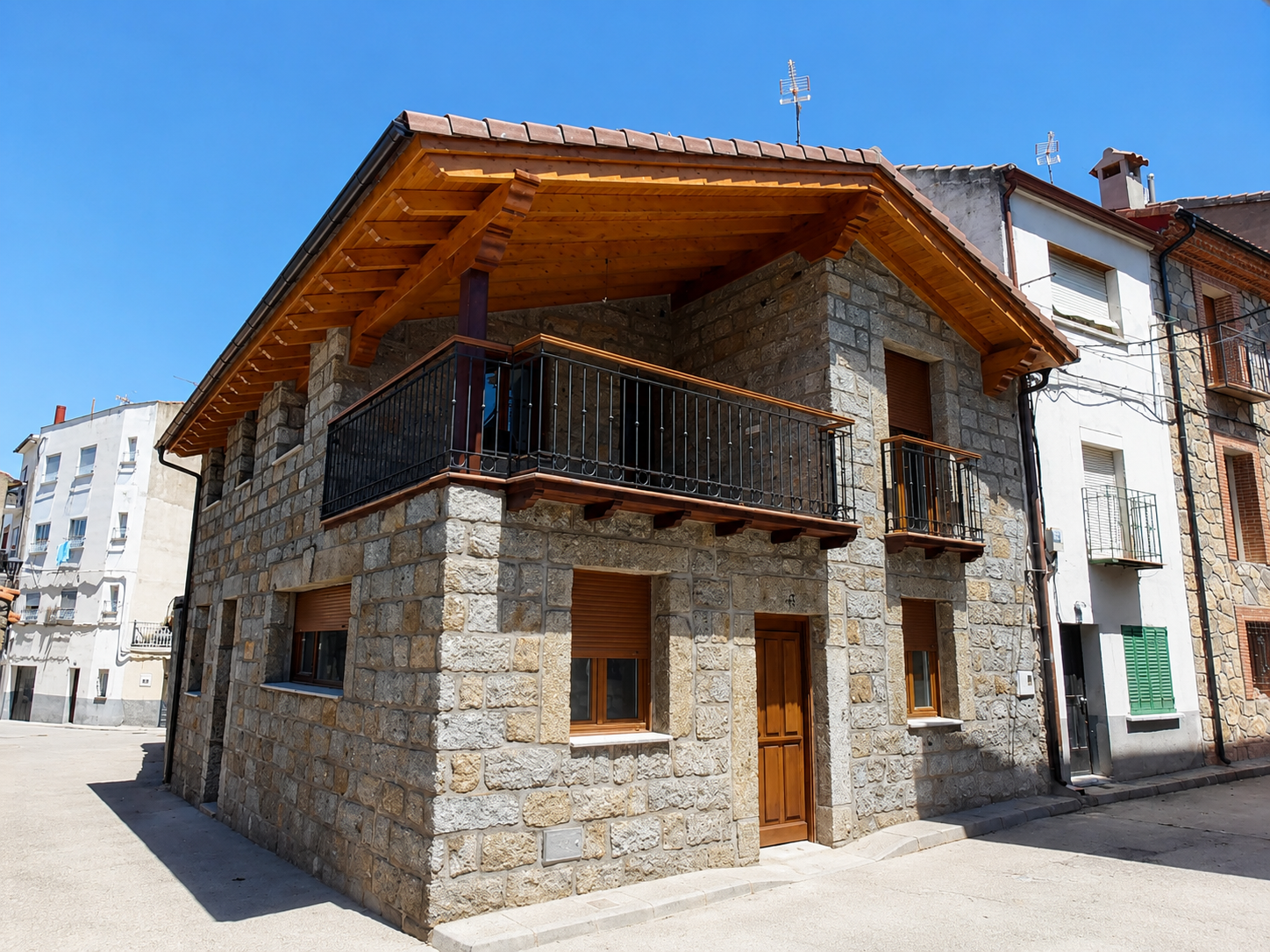 Vivienda de piedra con balcón y porche de madera realizada por Obras Jesús Pérez